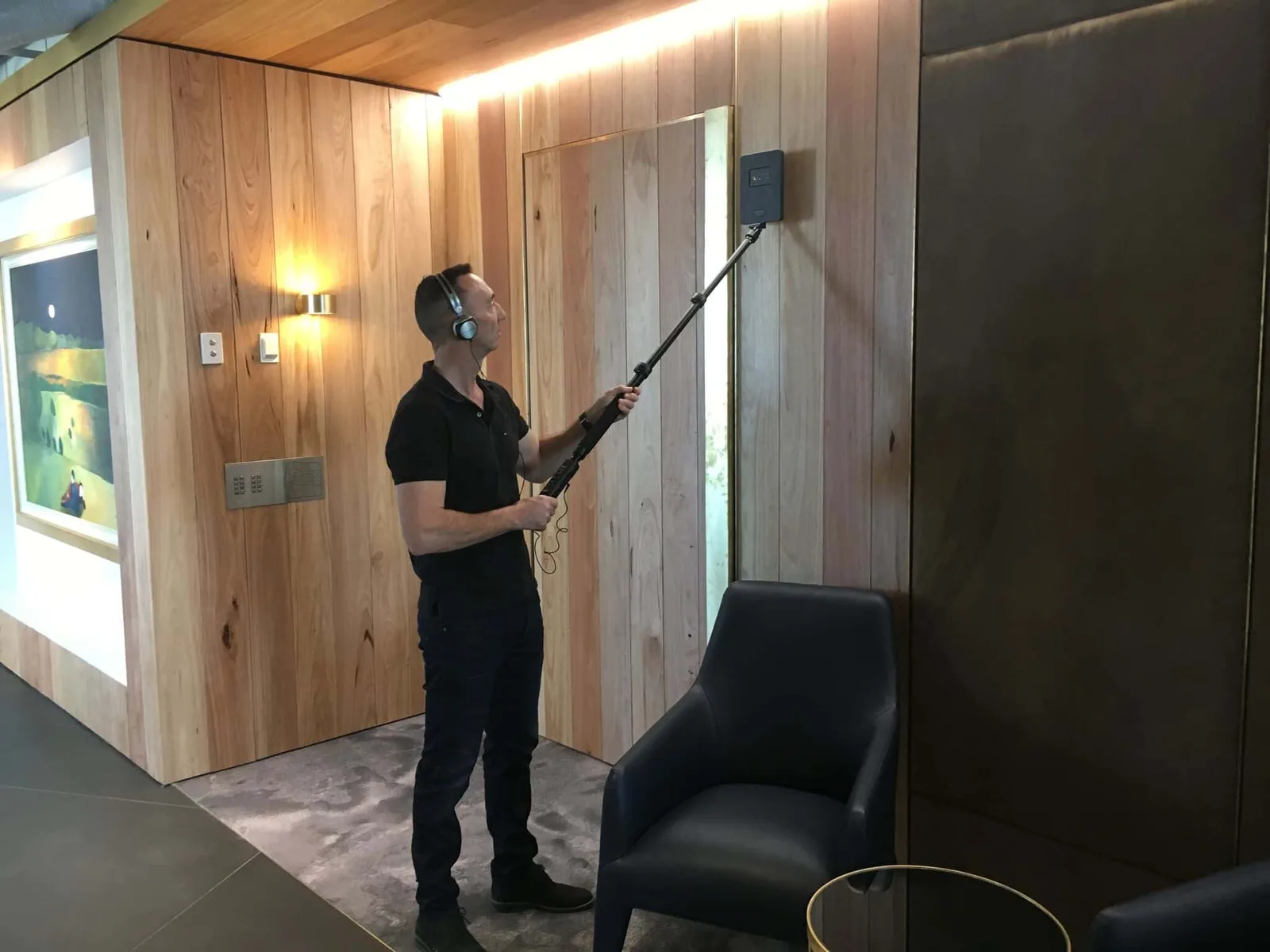 Security Tactics technician sweeping a timber-lined boardroom with a telescopic detection wand
